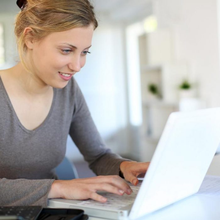 Beautiful young woman studying at home on laptop